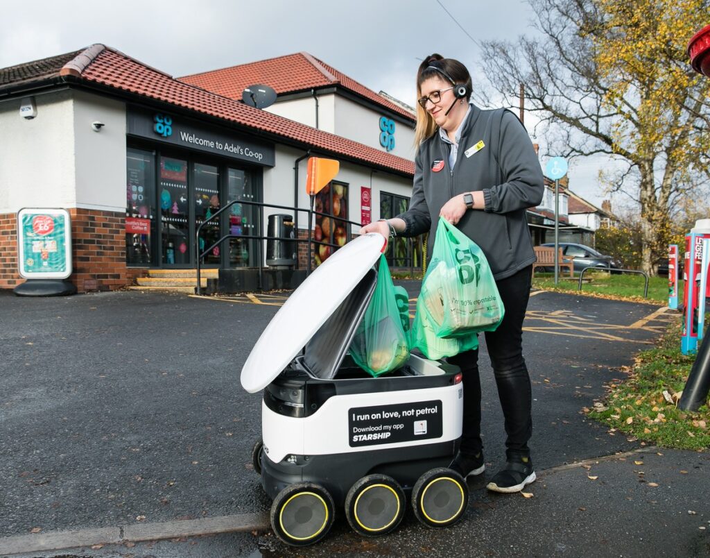 Coop staff loads a Starship robot with a customer's grocieries order outside Coop store in the United Kingdom