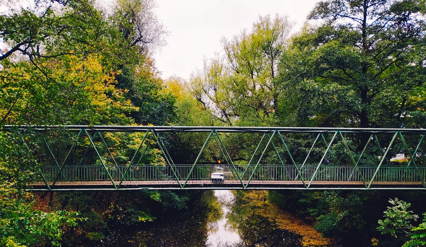 Robot crossing a bridge on a green environment