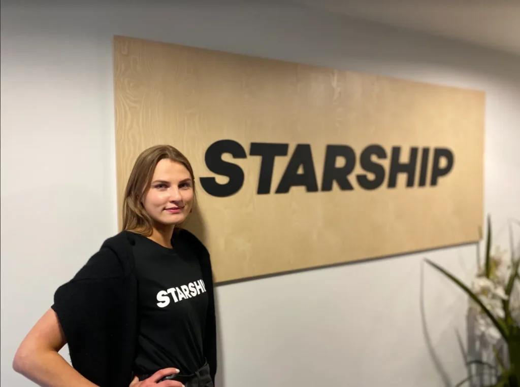 Karoliina standing netxt to a big Starship logo