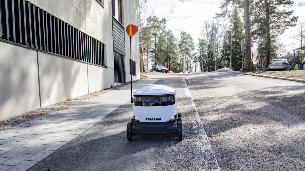 A Starship robot rolling on a street in Finland