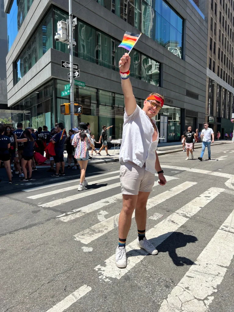 Boy standing a LGBTQ+ flag on Pride Parade