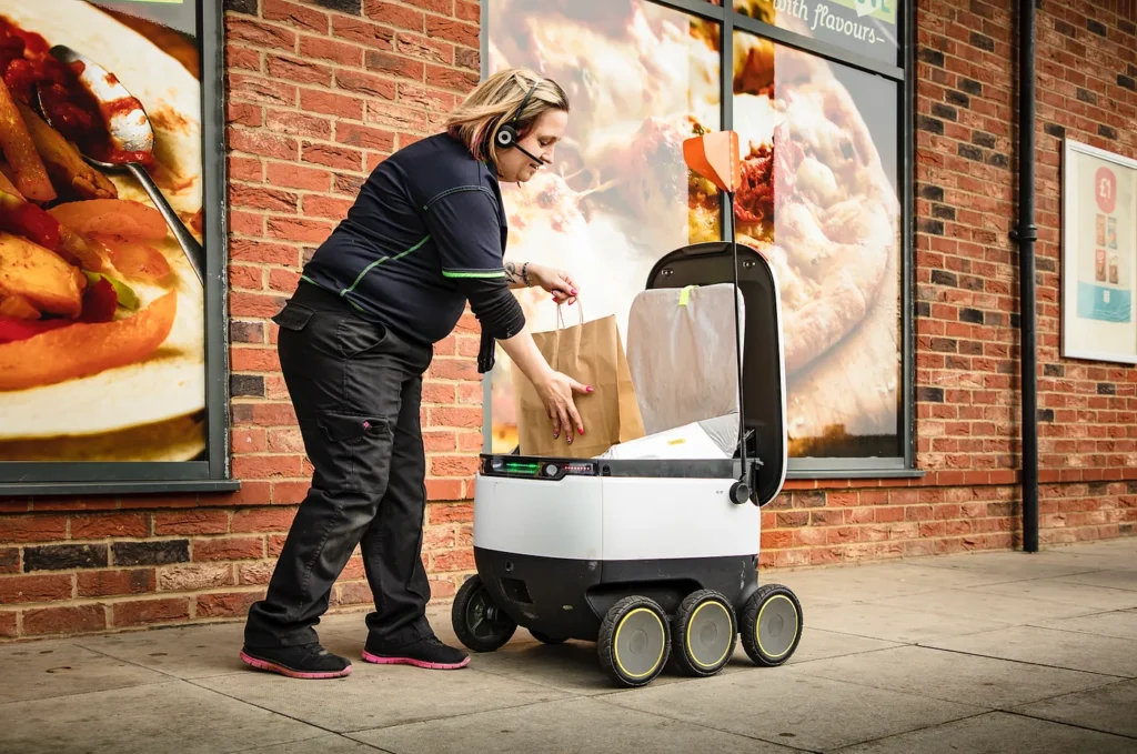 Worker placing a bag inside a Starship robot