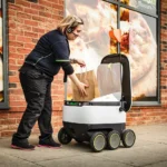 Worker placing a bag inside a Starship robot